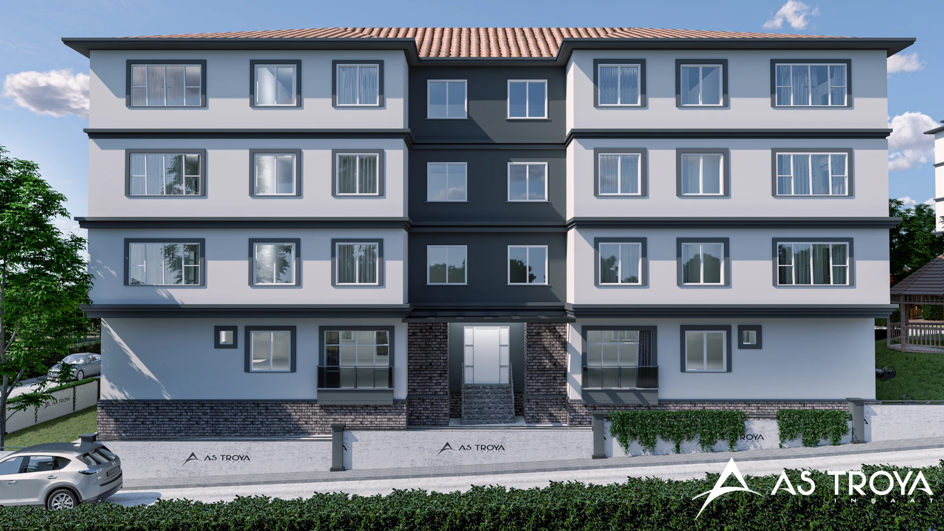 Bu resim, modern bir apartman bloğunun dış cephesini göstermektedir. Dört katlı yapı, büyük pencereleri ve modern mimari detaylarıyla dikkat çekmektedir. Binanın ön kısmında doğal taş dokusu kullanılarak estetik bir görünüm elde edilmiştir. Ayrıca çevresinde yeşil alanlar ve peyzaj düzenlemeleri yer alıyor, bu da yaşam alanına ferah bir atmosfer katmaktadır. Binanın ismi "AŞ Troya" olarak belirtilmiştir.
